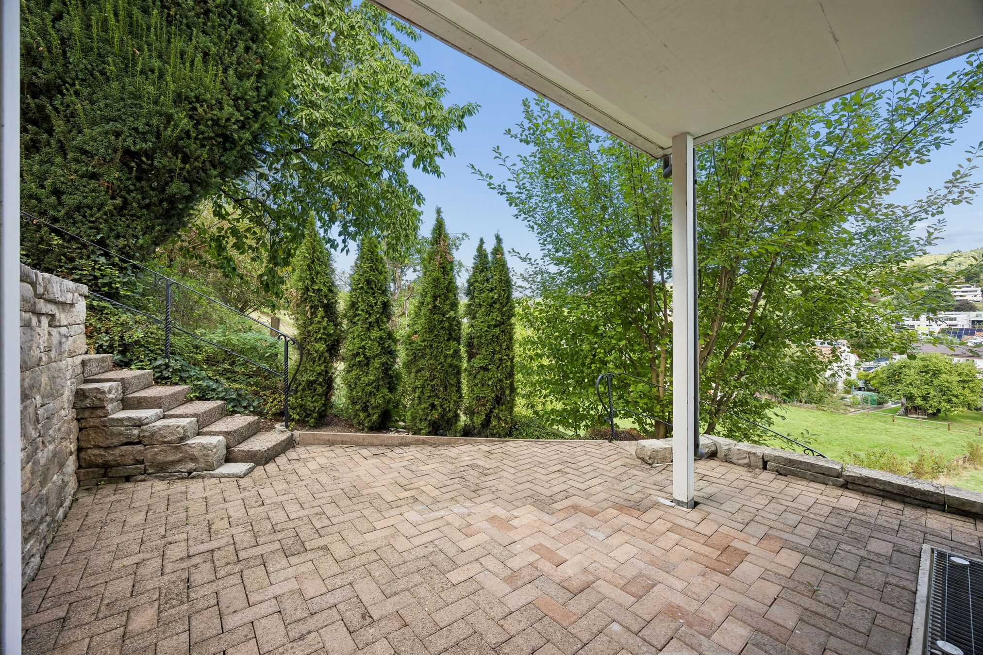 Überdachte Terrasse mit Natursteinmauer und Treppe